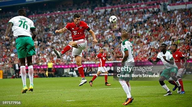 Robert Lewandowski of Bayern Muenchen jumps for a header with Fallou Diagne and Lamine Sane of Werder Bremen during the Bundesliga match between...