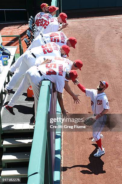 Bryce Harper of the Washington Nationals high-fives the pitchers in the bullpen before the game against the Colorado Rockies at Nationals Park on...