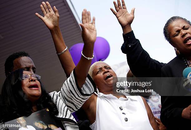 Diann Aldridge, center, the mother of Nykea Aldridge holds her hand in the air during a vigil for her daughter as her sister Jolinda Wade, right,...