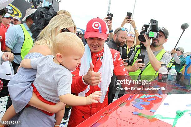 Kyle Larson, driver of the Target Chevrolet, girlfriend Katelyn Sweet and son Owen Larson affixe the winners decal to his car in Victory Lane after...