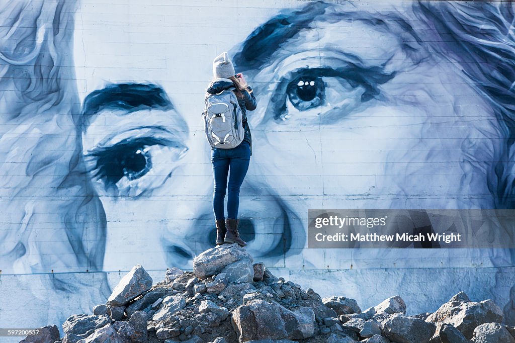 A woman admires a building mural.