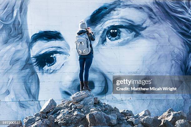 a woman admires a building mural. - arte de rua imagens e fotografias de stock