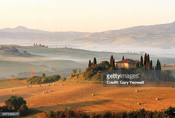 farmhouse in rolling tuscan landscape at dawn - toskana stock-fotos und bilder