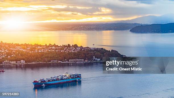 cargo ship through puget sound in sunset - puget sound stock pictures, royalty-free photos & images