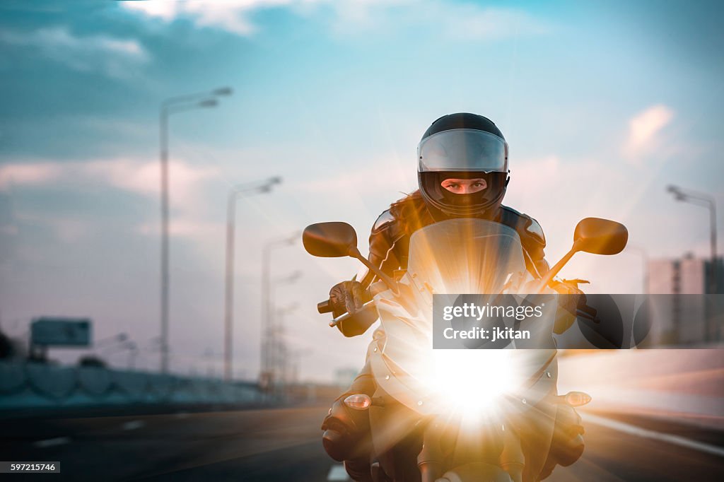 Woman drives on a motorcycle on a morning highway