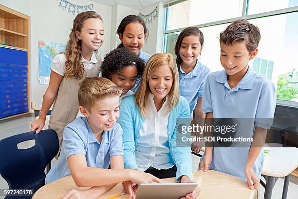 teacher and students use a digital tablet for education purpose - primary school children in uniform stock pictures, royalty-free photos & images