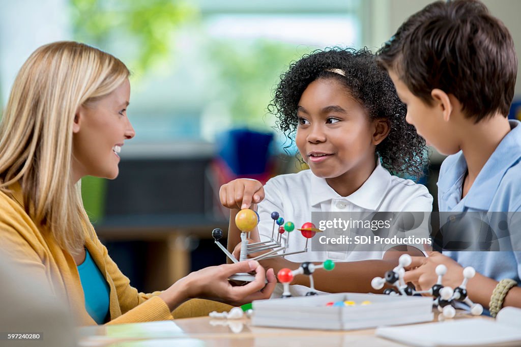 Young students and teacher in science class studying solar system