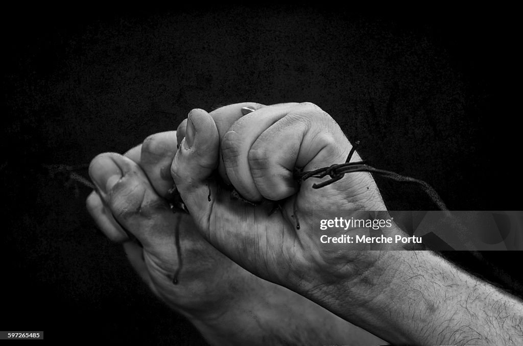 Hands pressing barbed wire