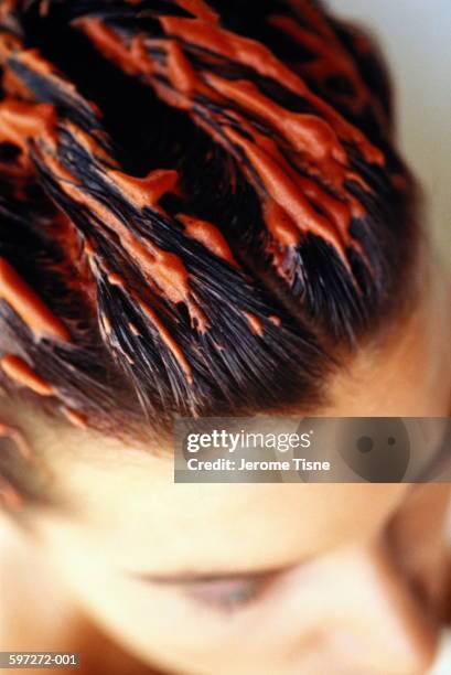 woman with orange colouring mousse combed through wet hair, close-up - haarkleur stockfoto's en -beelden