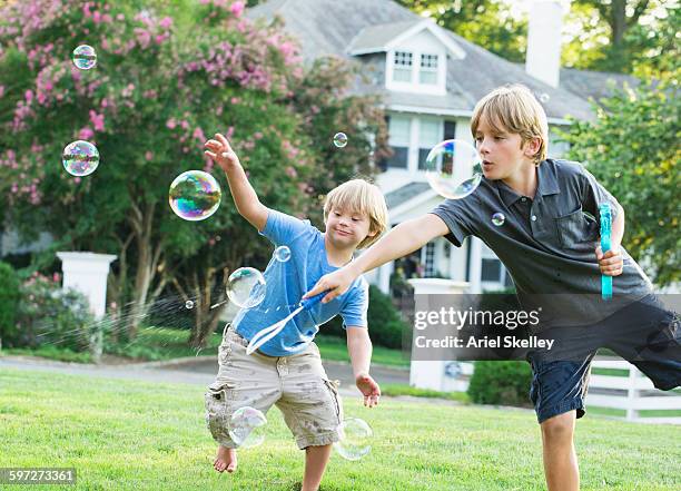 caucasian brothers playing with bubbles - standing on one leg stock-fotos und bilder