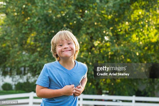 caucasian boy with down syndrome smiling outdoors - down's syndrome fotografías e imágenes de stock