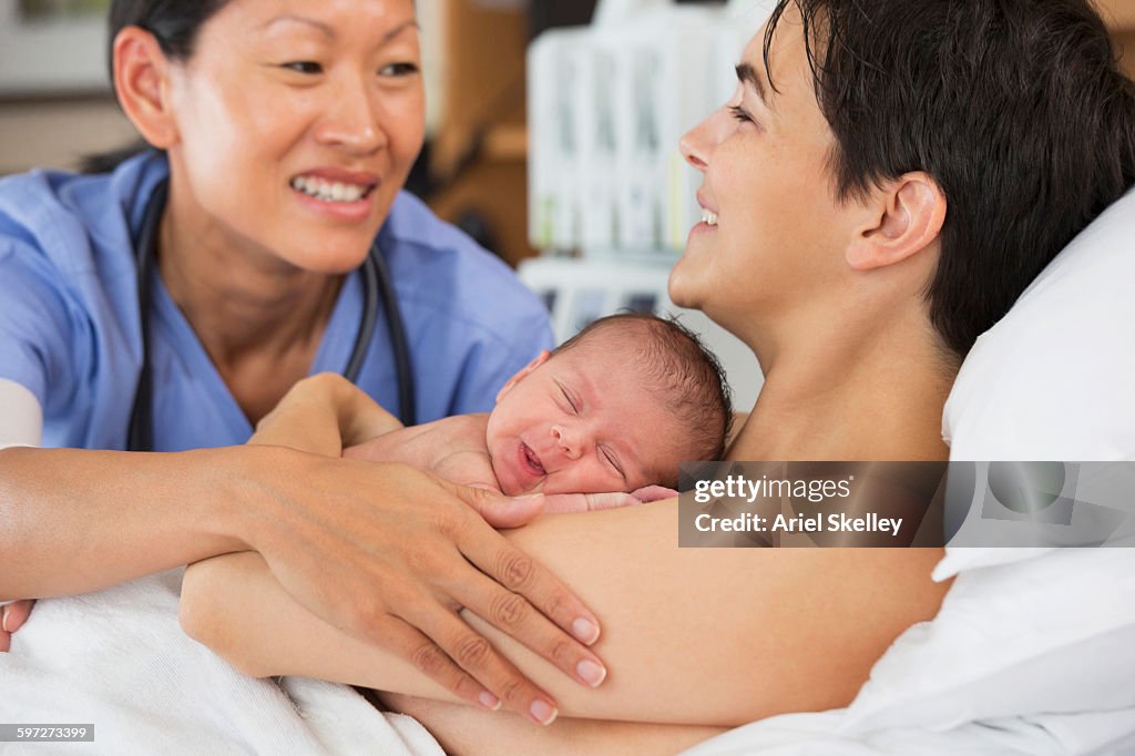 Nurse comforting mother and newborn in hospital