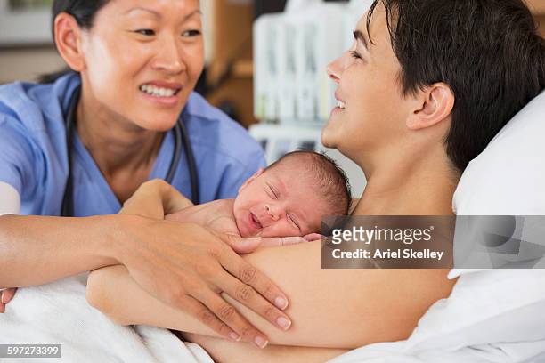 nurse comforting mother and newborn in hospital - family photo in the delivery room stock pictures, royalty-free photos & images