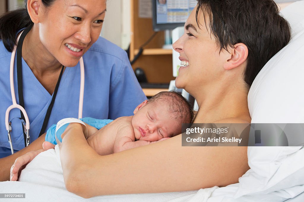 Nurse comforting mother and newborn in hospital