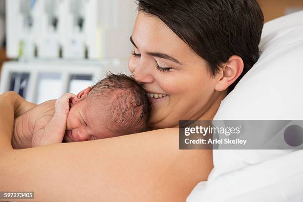 mother holding newborn infant in hospital - borstkas stockfoto's en -beelden