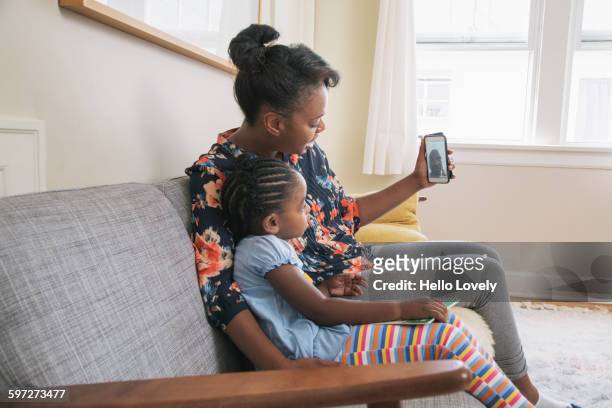 African American mother and daughter video chatting on cell phone