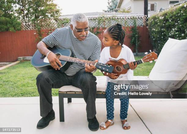 african american grandfather teaching granddaughter to play guitar - usa pensioners outdoors stock-fotos und bilder