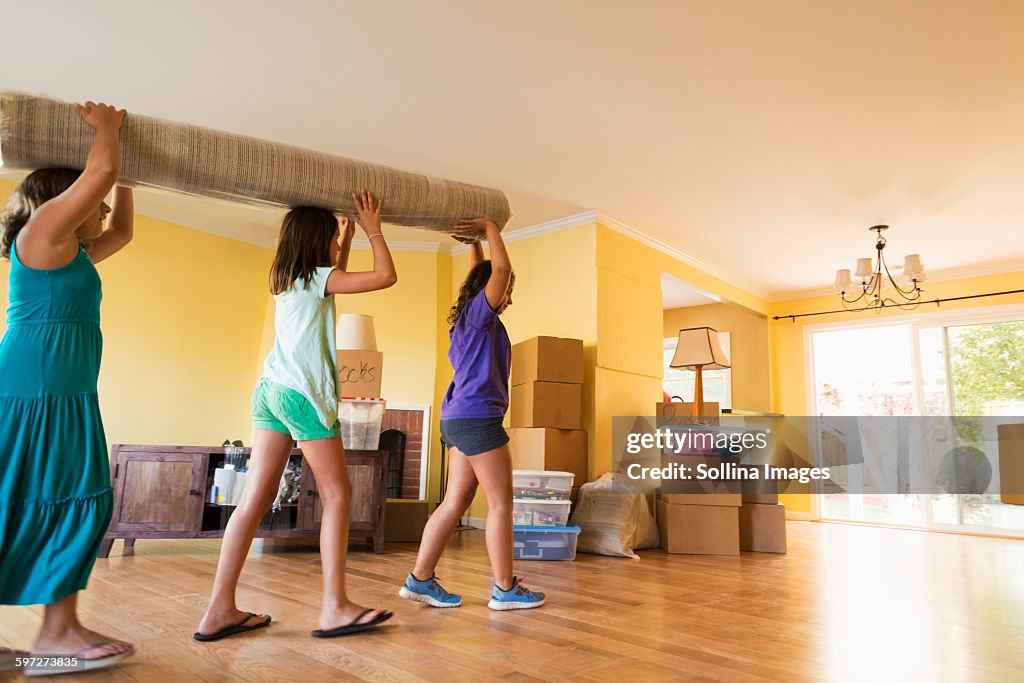 Children carrying carpet in new house