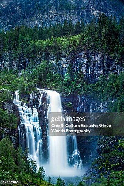 skjervsfossen waterfall surrounded by pine forest and huge cliffs, near voss, norway - voss fotografías e imágenes de stock