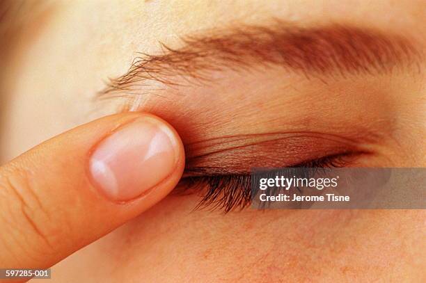 woman blending make-up onto eyelid with finger, section - eye make up ストックフォトと画像