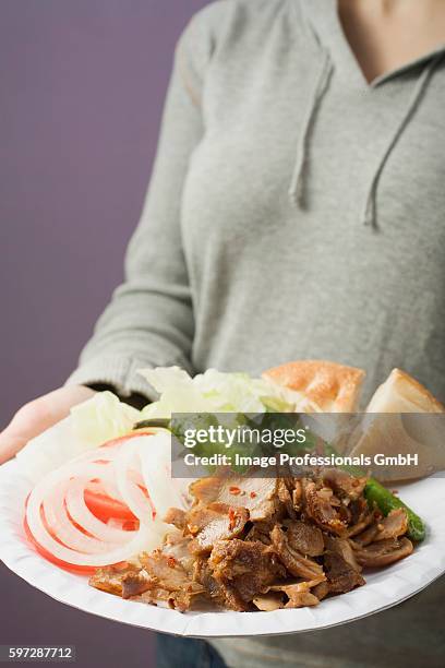 woman holding paper plate of d??ner meat, vegetables & flatbread - dner stock-fotos und bilder