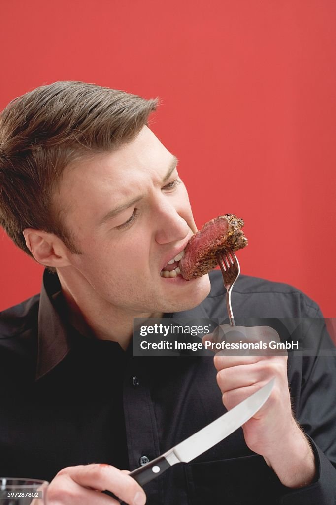 Man biting a tough piece of beef steak