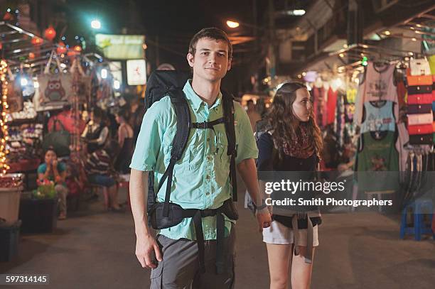 caucasian tourists holding hands in market at night - chiang mai sunday market stock pictures, royalty-free photos & images