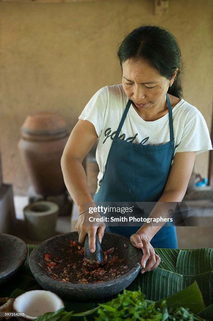 Asian chef grinding spices in outdoor kitchen