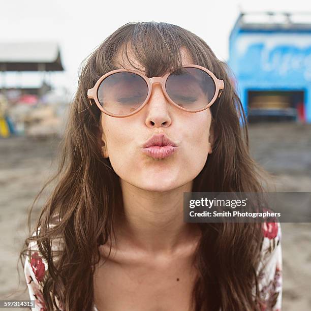 caucasian woman in sunglasses puckering to kiss at beach - kiss face stock pictures, royalty-free photos & images