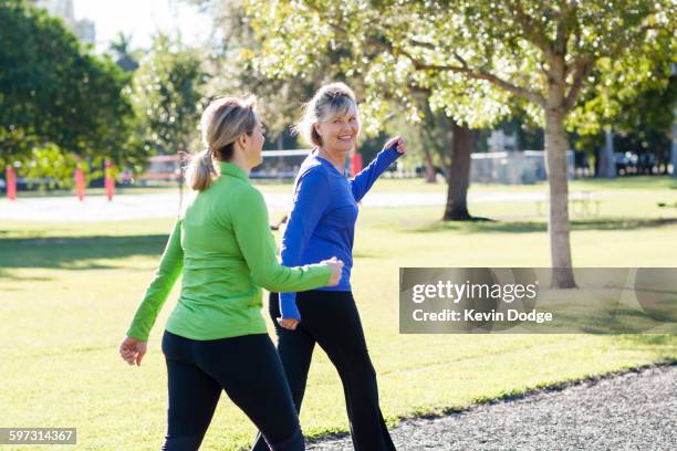 caucasian women walking in park - wandelen lichaamsbeweging stockfoto's en -beelden