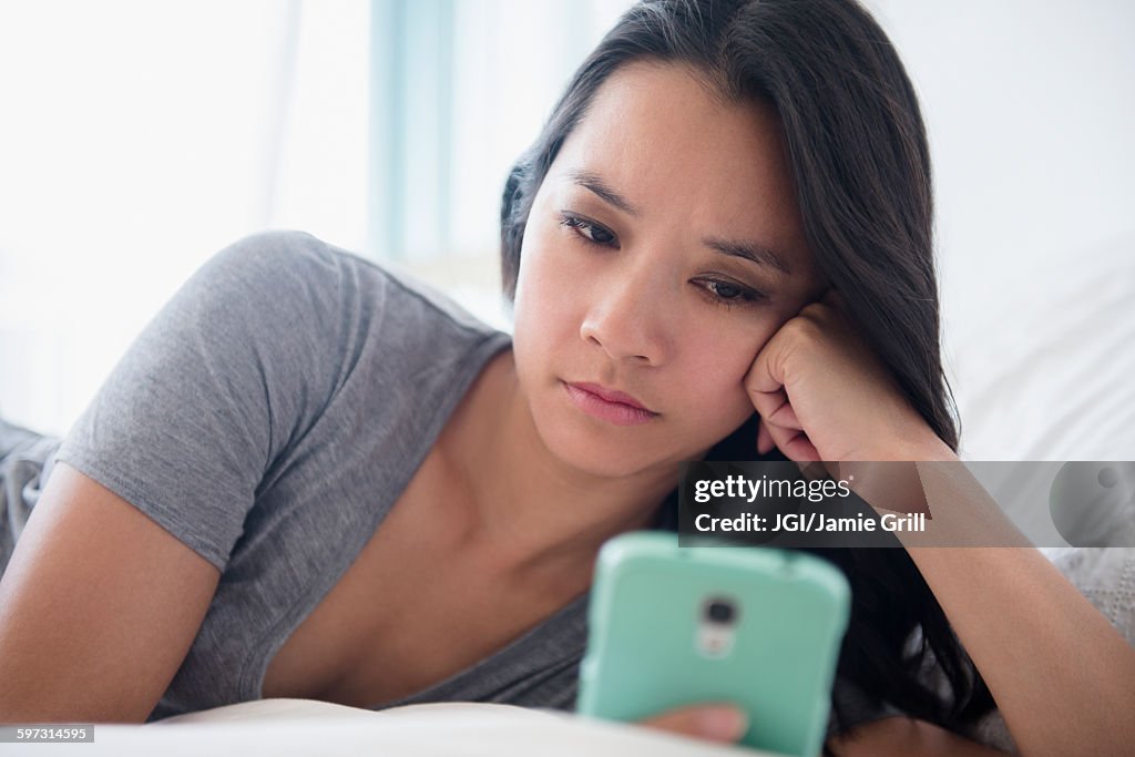 Chinese woman using cell phone on bed