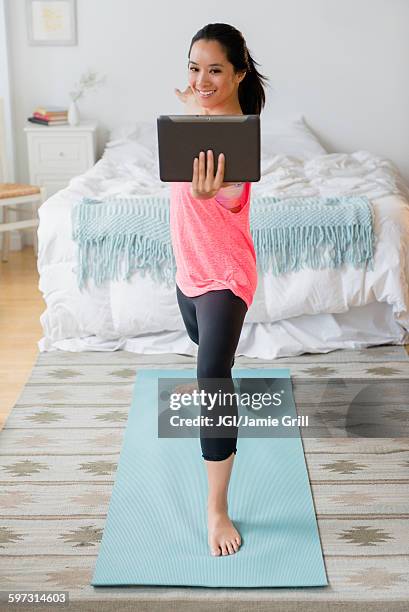 chinese woman practicing yoga with digital tablet - only women videos stock pictures, royalty-free photos & images