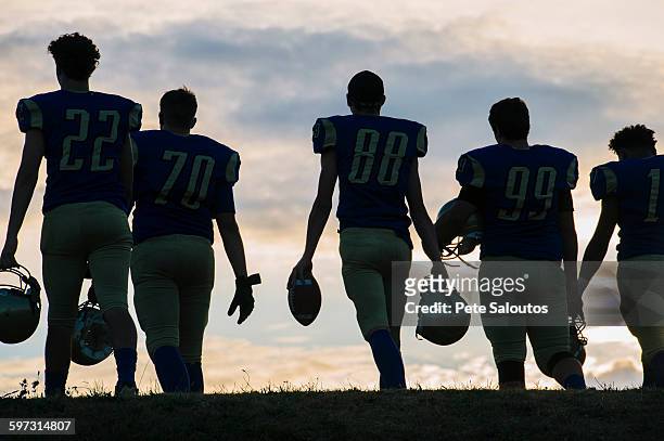 group of young american football players walking away, rear view - american football uniform stock pictures, royalty-free photos & images