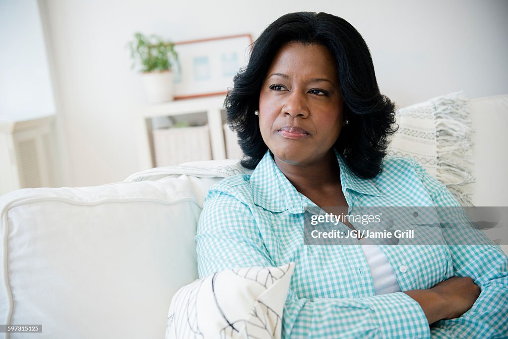 Unhappy Black woman sitting on sofa