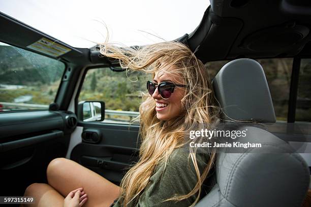 young woman with windswept long blond hair on the road in jeep - sunroof stock pictures, royalty-free photos & images