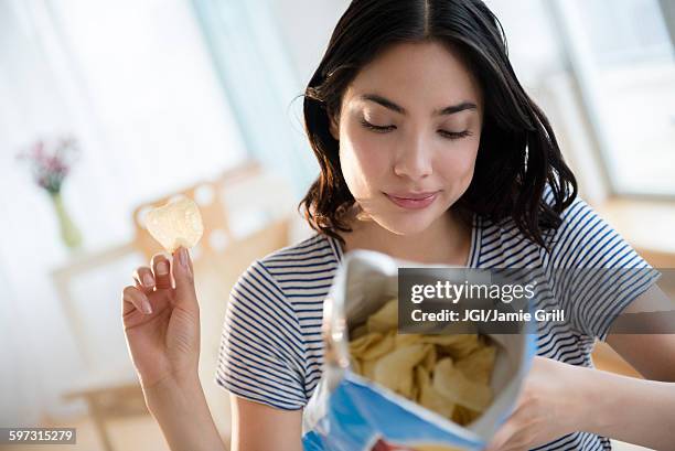 hispanic woman reading ingredients on bag of potato chips - patatas fritas tentempié fotografías e imágenes de stock
