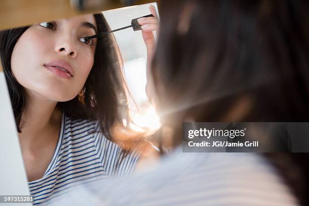 hispanic woman applying mascara in mirror - applying mascara stock pictures, royalty-free photos & images