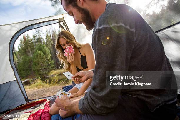 young couple sitting in tent playing cards, lake tahoe, nevada, usa - camping games stockfoto's en -beelden