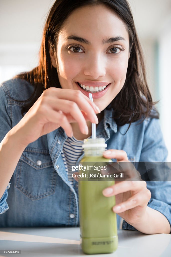 Hispanic woman drinking green juice