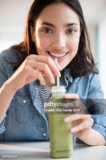 hispanic woman drinking green juice - detox drink stock pictures, royalty-free photos & images