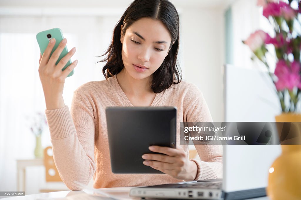 Hispanic woman using cell phone and digital tablet
