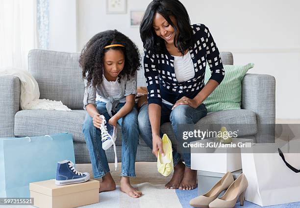 mother and daughter trying on shoes on sofa - child high heels stock pictures, royalty-free photos & images