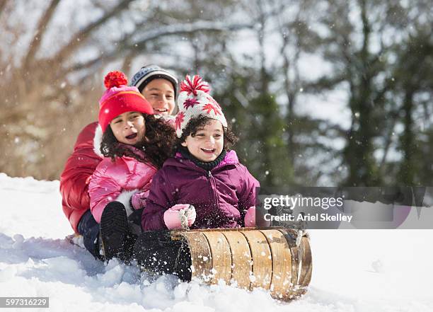 hispanic family sledding in snow - tobogganing 個照片及圖片檔