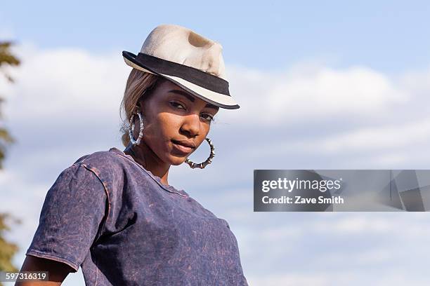 low angle view of young woman wearing fedora and hoop earrings looking at camera - hoop earring bildbanksfoton och bilder