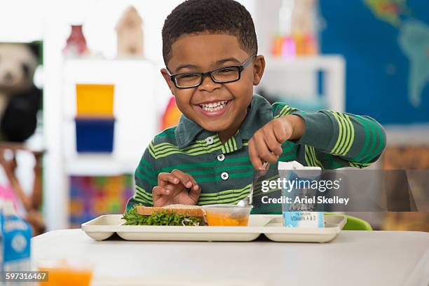 black boy eating lunch at school - school lunch stockfoto's en -beelden