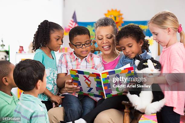 kindergarten teacher reading to class - daycare teacher stock pictures, royalty-free photos & images