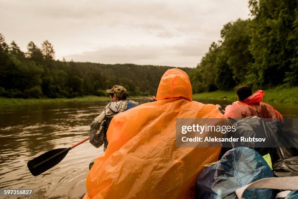 people wearing ponchos on boat in river - poncho stock pictures, royalty-free photos & images