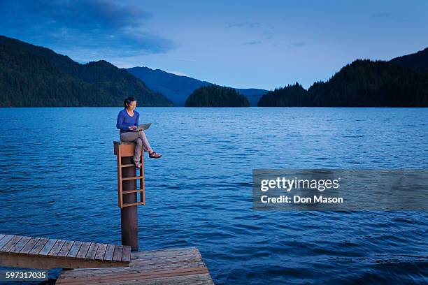 japanese woman sitting on wooden dock at lake - lake whatcom foto e immagini stock