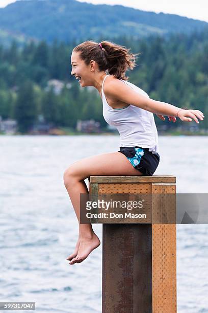 mixed race girl sitting on wooden pedestal at lake - lake whatcom foto e immagini stock