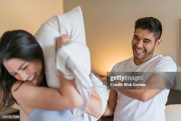 hispanic couple having pillow fight - kissenschlacht paar stock-fotos und bilder
